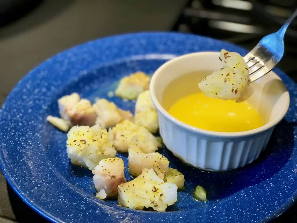 Fish dipped in yellow sauce on a blue plate.