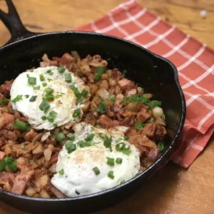 Hash browns, bacon, eggs, and green onions in a skillet.