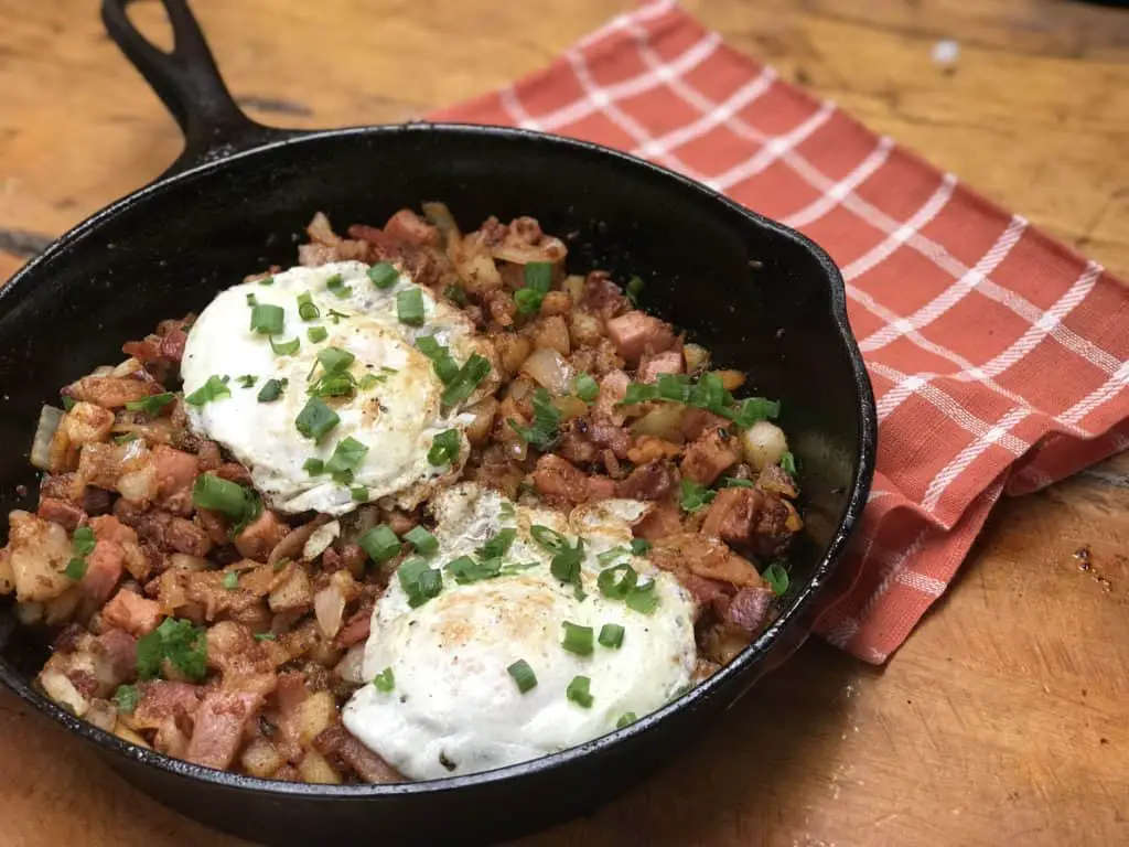 Hash browns, bacon, eggs, and green onions in a skillet.