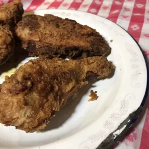 Three crispy fried chicken drumsticks on a plate.