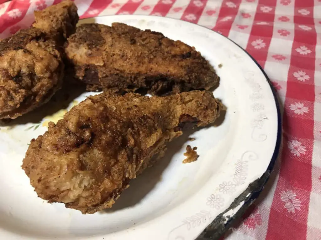 Three crispy fried chicken drumsticks on a plate.