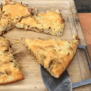 Cheesy pizza slices on a cutting board.