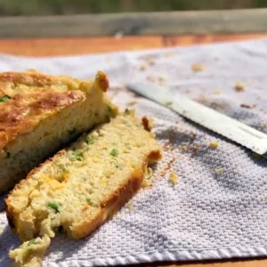 Sliced cornbread with green onions on a towel.