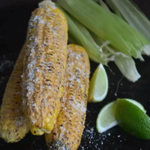 Grilled corn on the cob with lime wedges.