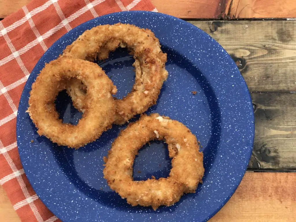 Three crispy onion rings on blue plate.