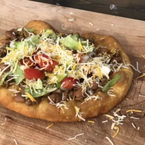 Fried bread topped with meat, cheese, lettuce, and tomatoes.