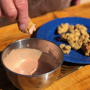 Dipping fried food in pink sauce.