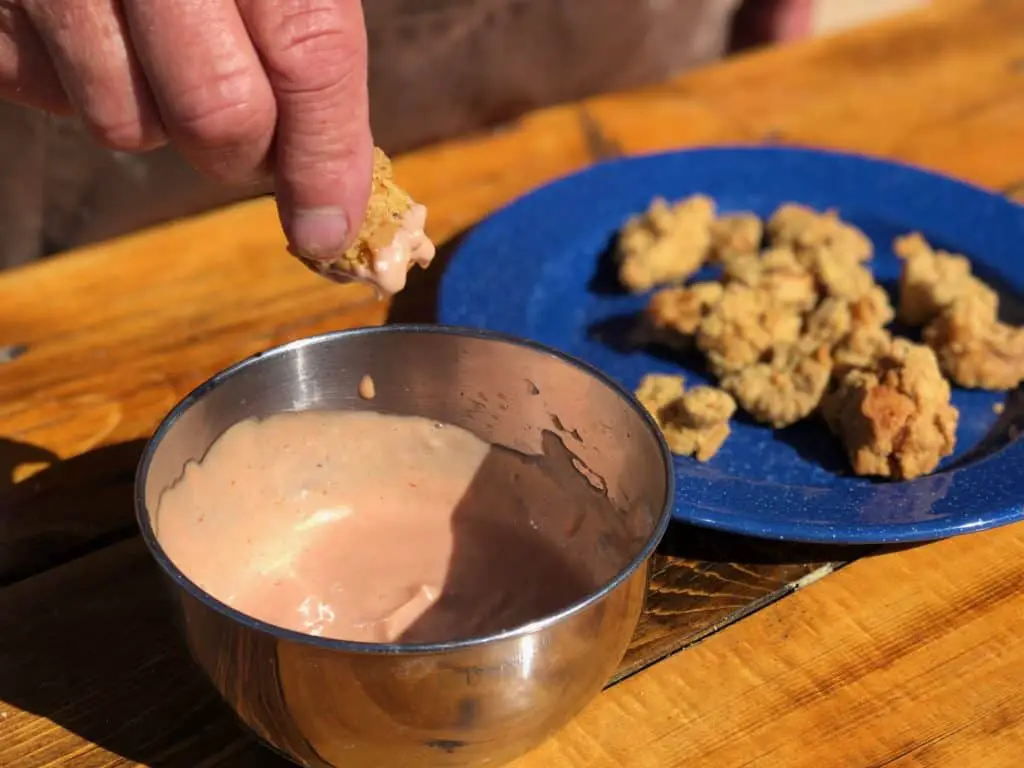 Dipping fried food in pink sauce.