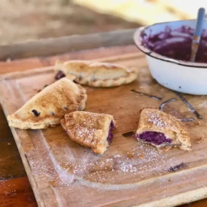 Purple-filled pastries on a wooden board.