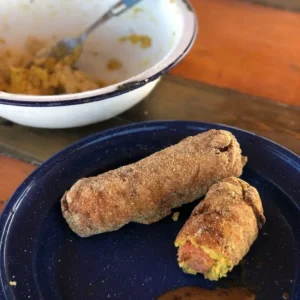 Two corn dogs on blue plate with sauce.