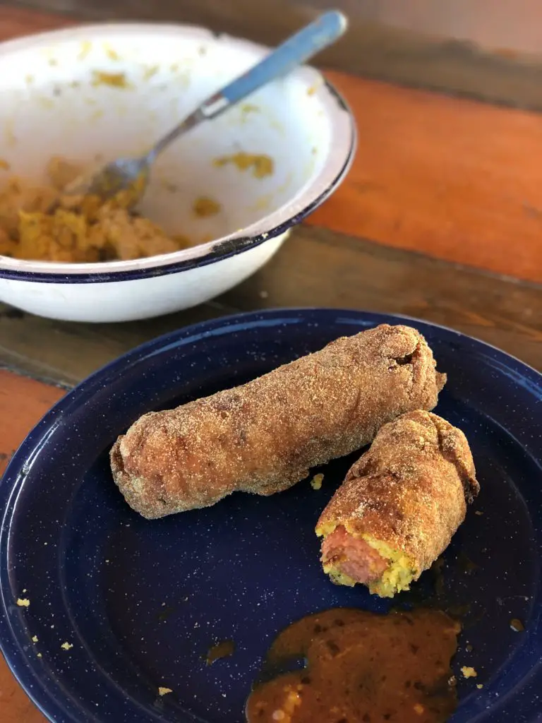 Two corn dogs on blue plate with sauce.