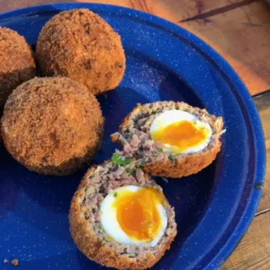 Scotch eggs on a blue plate.