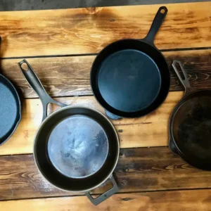 Four cast iron skillets on wood table.