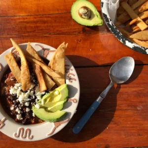 Bowl of chili with avocado and chips.