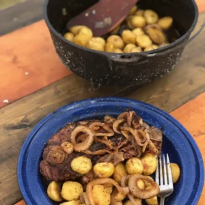 Steak, potatoes, and onions on a blue plate.