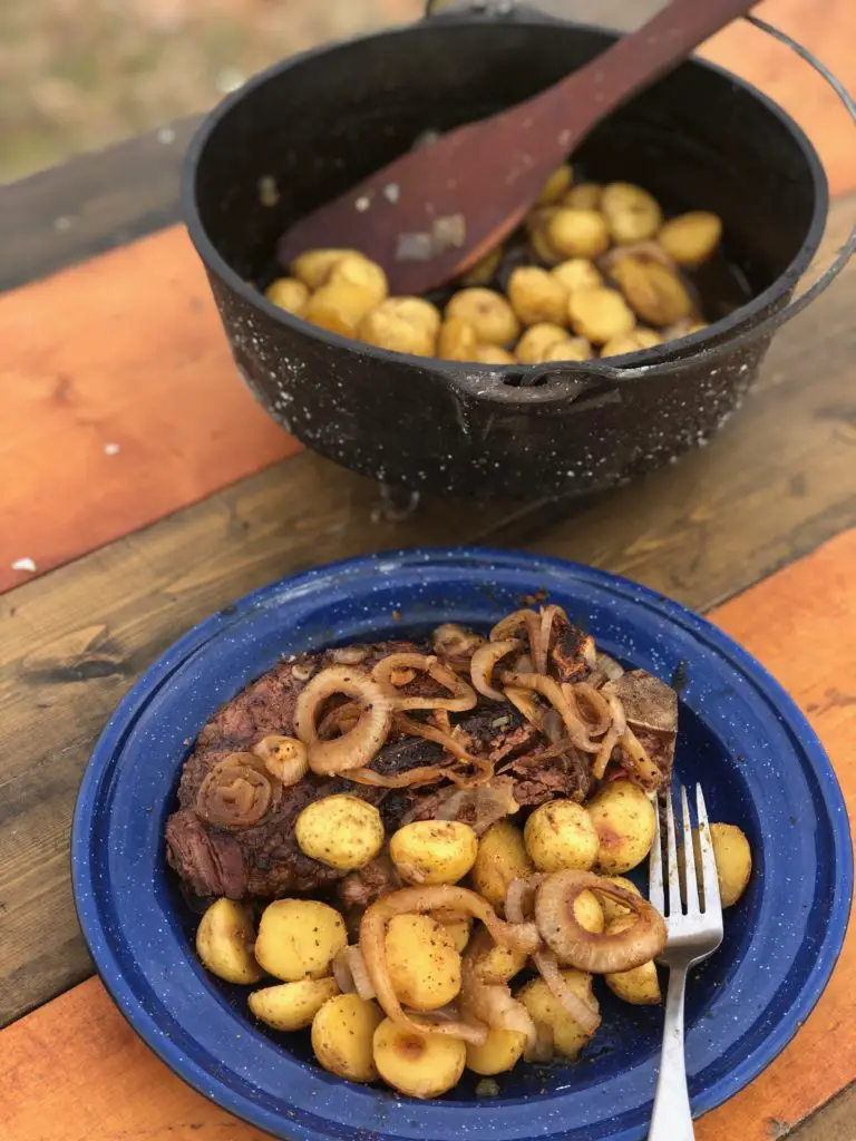 Steak, potatoes, and onions on a blue plate.