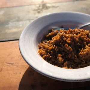 A white bowl of brown rice on a table.