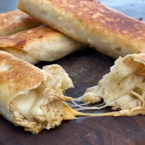 Crispy chicken and cheese quesadillas on wood board.