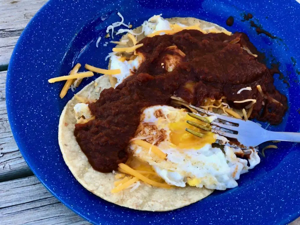 Tortilla with eggs, cheese, and salsa on a blue plate.