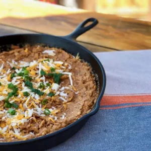 Cheesy dip with green onions in a skillet.