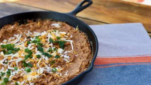 Cheesy dip with green onions in a skillet.