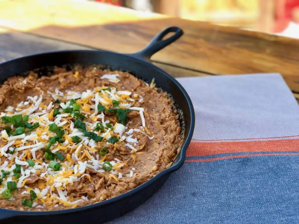 Cheesy dip with green onions in a skillet.