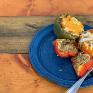 Stuffed peppers with cheese on a blue plate.