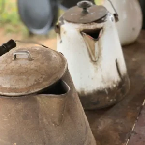 Three vintage metal pitchers on a table.