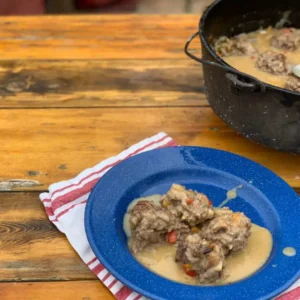 Meatballs in creamy sauce on a blue plate.