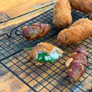 Fried jalapeno poppers on wire rack.