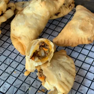 Fried pastries with meat filling on wire rack.