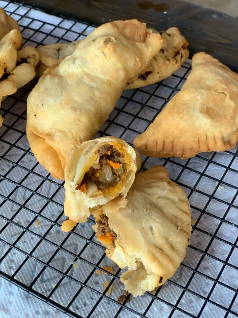 Fried pastries with meat filling on wire rack.