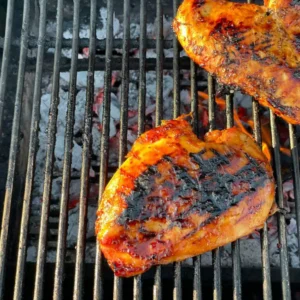 Two grilled chicken breasts on a grill.