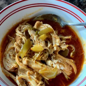 Bowl of shredded chicken in red sauce.