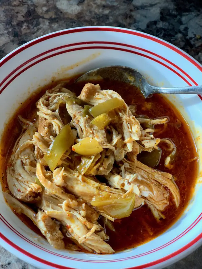 Bowl of shredded chicken in red sauce.