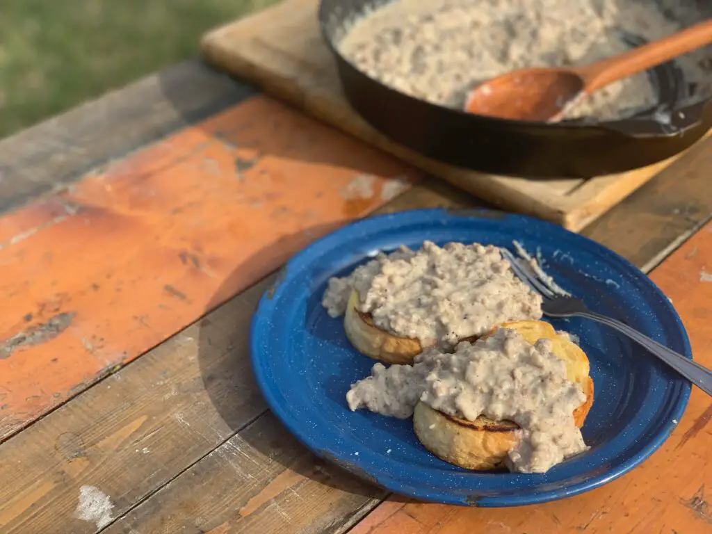 Two biscuits with gravy on a blue plate.