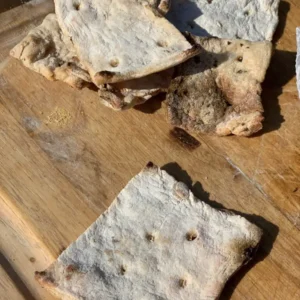 Stack of crispy flatbread on a wooden board.