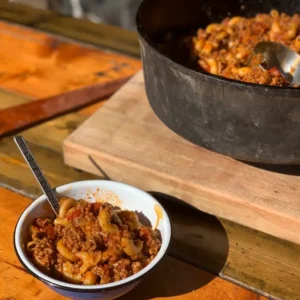 A bowl of goulash with a spoon.