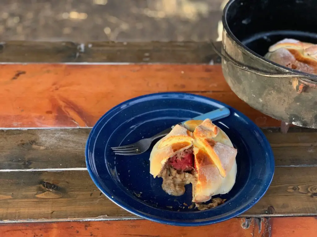 Half-eaten pastry on blue plate, wooden table.