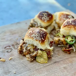 Closeup of four cheeseburgers on buns.