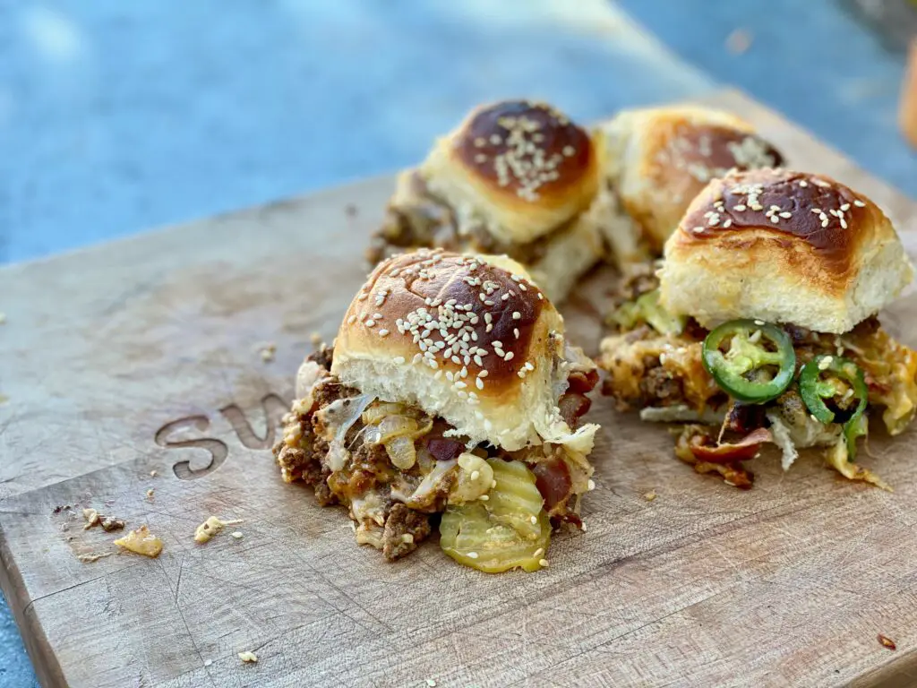 Closeup of four cheeseburgers on buns.