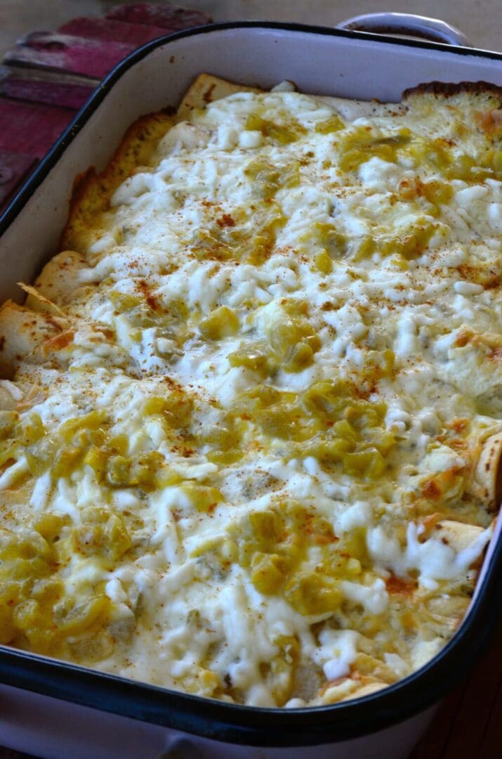 Cheesy green chile enchiladas in a baking dish.