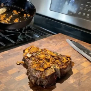 Grilled steak with mushrooms on cutting board.