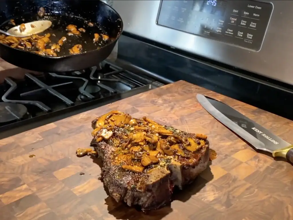 Grilled steak with mushrooms on cutting board.