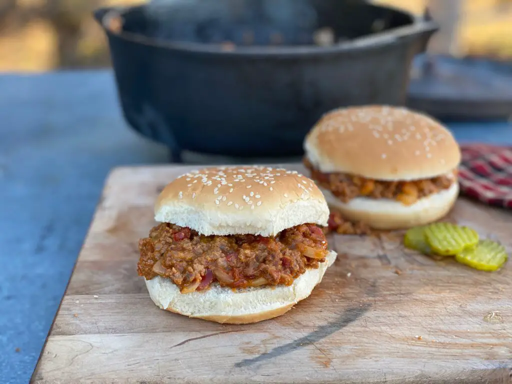 Two sloppy joe sandwiches on a cutting board.