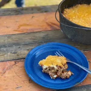 A slice of cheesy casserole on a blue plate.