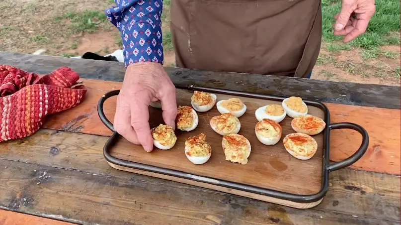 Deviled eggs on a wooden tray.