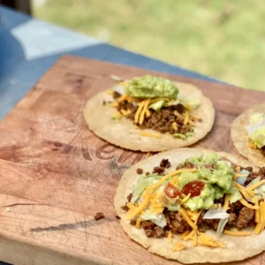 Three tacos with meat, cheese, and guacamole.