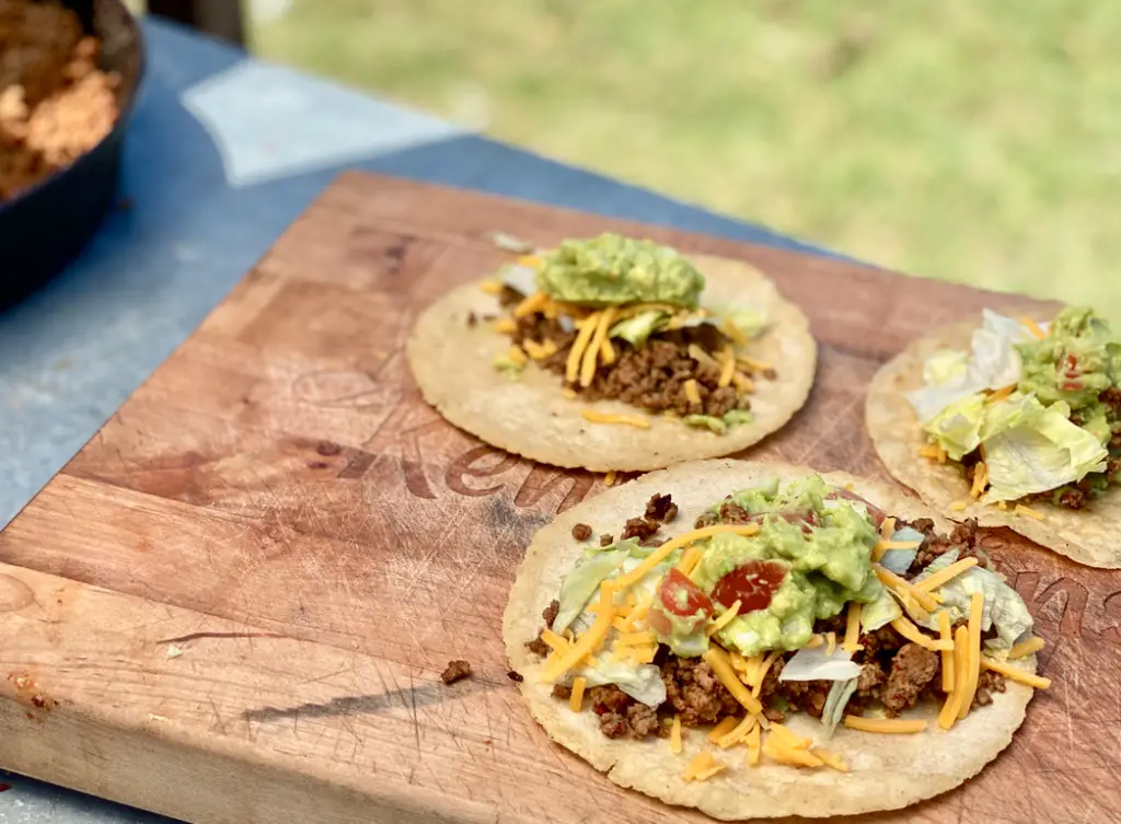 Three tacos with meat, cheese, and guacamole.