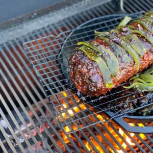 Grilled meat with green peppers on a grill.